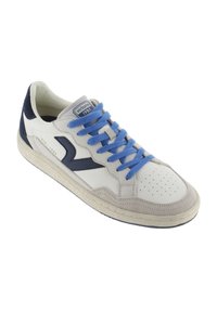 Sneaker bianca e navy con lacci blu, materiali in suede e pelle, punta perforata, suola piatta in gomma e patch con logo sulla linguetta.