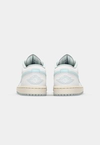 Baskets en cuir blanc avec des accents bleu clair, dotées d'un col rembourré, d'une semelle intermédiaire texturée et d'un logo brodé à l'arrière.