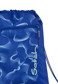 Blue drawstring backpack featuring a wavy textured pattern in lighter blue, with a zippered pocket and “Satch” logo in green.