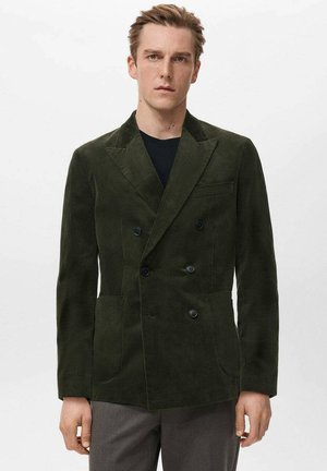 Doppelreihige Cordjacke in Dunkelgrün. Mit Reverskragen, zwei Fronttaschen und schwarzen Knöpfen. Strukturierter, taillierter Schnitt.