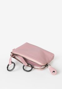 Borsetta in pelle rosa con chiusura a cerniera, accenti circolari in metallo nero e una superficie liscia. Forma rettangolare compatta con anelli laterali.