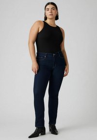 Svart ribbad linne topp i kombination med mörkblå skinny jeans. Jeansen har en knappstängning fram och fem fickor, kompletterat med svarta ankle boots.