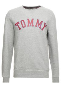 Sudadera gris de tejido mezcla de algodón, con cuello redondo, mangas largas y lettering rojo "TOMMY" en un diseño arqueado.