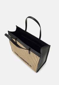Tkáná taška přes rameno s černými koženými lemy. Má černé rukojeti a texturovaný otevřený vzor tkaní v přírodních tónech. Viditelná je vnitřní kapsa.