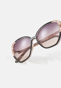 Black oversized sunglasses with glittery gold accents. Gradient lenses transition from dark to light purple, featuring a decorative frame.