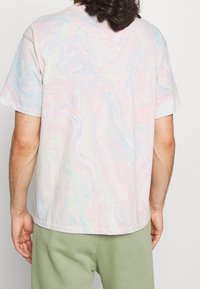 T-shirt à manches courtes en tie-dye pastel, avec des motifs tourbillonnants en rose, bleu et crème, fabriqué en coton doux.