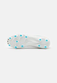 Suola di una scarpa da ginnastica bianca con accenti blu, caratterizzata da numerosi tacchetti per la trazione e una superficie testurizzata con linee di design sottili e perforazioni.