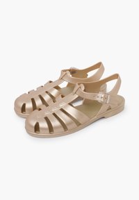 Gold-colored plastic sandals with an open design, featuring cut-out strips and an adjustable buckle strap for secure fit.