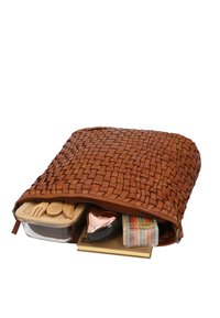 Brown woven leather bag unzipped, showing wooden utensils, a lunch container, a hairbrush, and a package of colorful macarons inside.