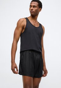 Must mustakangas puuvillast, millele on lisatud kerge mustade lühikesed püksid, millel on peene diamantmuster ja elastne vöökoht.