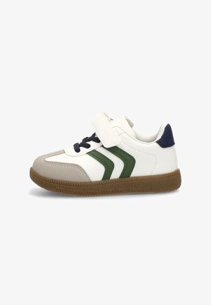 Deportiva blanca con acentos en verde y marino, que presenta una correa de velcro, una puntera texturizada en gris, suela de goma y un diseño de chevron lateral.