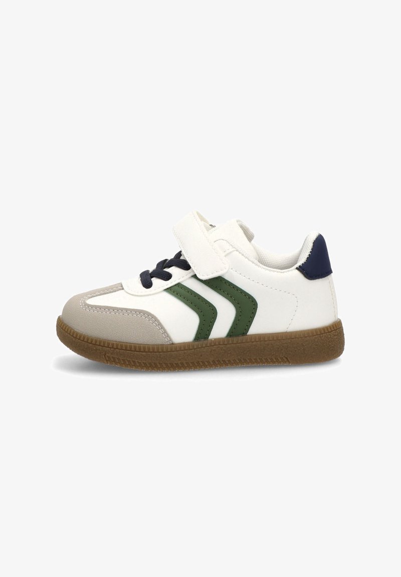 Deportiva blanca con acentos en verde y marino, que presenta una correa de velcro, una puntera texturizada en gris, suela de goma y un diseño de chevron lateral.