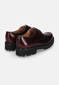 Bordeauxfarbene Lederschuhe mit polierter Oberfläche, runder Zehenform, passenden Schnürsenkeln und einer dicken, strukturierten schwarzen Gummisohle.