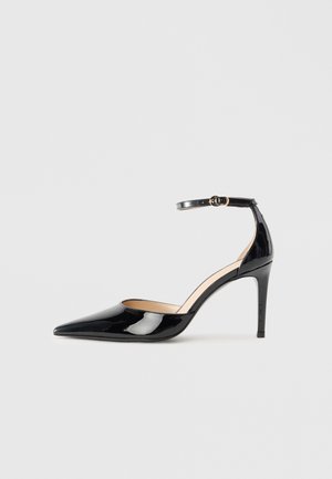 Black patent leather high heel shoe with a pointed toe, an ankle strap, and a sleek design. Features a slender heel and smooth texture.
