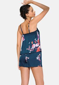 Rompers floraux marine à bretelles spaghetti, avec un corsage smocké et des shorts. Fabriqué en tissu léger, mettant en valeur des motifs floraux roses et blancs.