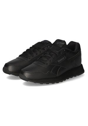 Par de zapatillas Reebok negras de perfil bajo con cierre de cordones, suelas texturizadas y logos de la marca en los laterales y lengüetas.