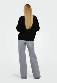 Üks suur must kudum, ümmarguse kaelusega, koos heledate hallide laiade pükste jaotusega. Sile tekstuur, minimalistlik disain, juhuslik stiil.