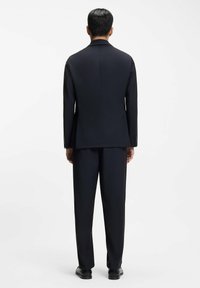 Granatowy garnitur o klasycznym kroju, z dopasowanym fasonem, klapami z wycięciem i gładką tkaniną. Spodnie w kolorze i stylu odpowiadającym marynarce.