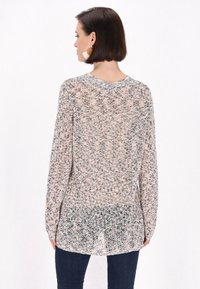 Lekki sweter dzianinowy w pastelowych kolorach z luźnym krojem, długimi rękawami i zaokrąglonym dołem. Tekstura jest otwarta i przewiewna.