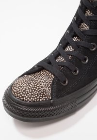 Černé vysoké tenisky s texturovaným semišovým svrškem a vzorovanou látkovou špičkou. Mají černé tkaničky a gumovou podr�ážku s diamantovou texturou.