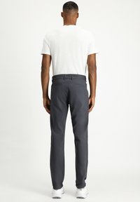 Grijze broek van gestructureerde stof, met een rechte pijp en achterzakken, gecombineerd met een eenvoudig wit overhemd met korte mouwen.