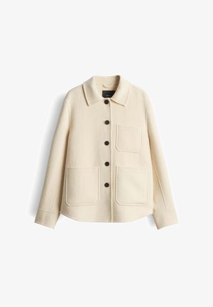 Roomkleurig wollen jasje met kraag, knoopsluiting aan de voorkant, twee opgestikte zakken en donkerbruine knopen. Heeft een textuurstof.