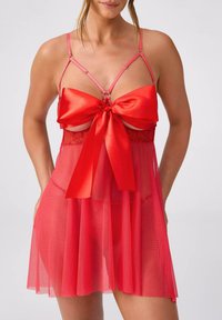 Czerwona przezroczysta bielizna babydoll z satynową kokardą, regulowanymi ramiączkami i koronkowymi detalami. Lekka tkanina z warstwową spódniczką.
