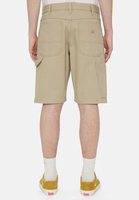 Beige cargo shorts dengan saku jahitan, potongan longgar, dan jahitan diperkuat. Fitur saku utilitas di sisi, dan pinggang datar.