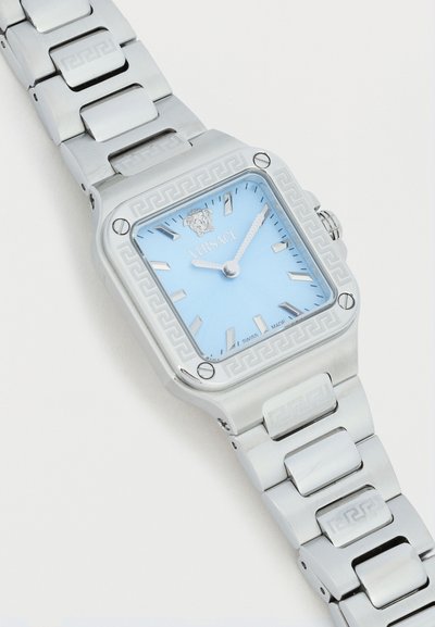 Ασημένιο ρολόι Versace από ανοξείδωτο ατσάλι με ανοιχτό μπλε τετράγωνο καντράν, λογότυπο Μέδουσα και μοτίβο ελληνικού κλειδιού στη στεφάνη και τους συνδέσμους του μπρασελέ.