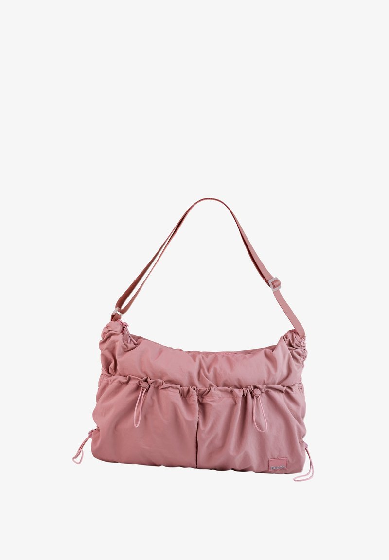 Pink nylon bag with a slouchy design, featuring gathered details, two front pockets, an adjustable strap, and drawstring accents.