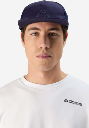 Cappellino blu navy con visiera piatta e lati in rete, con un logo ricamato scuro. Il modello indossa una t-shirt bianca a girocollo con branding.