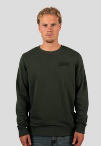 Sudadera de color verde oscuro hecha de una mezcla de algodón, con un cuello redondo y puños acanalados. En el frente se muestra el texto en relieve "WRONG FRIENDS."