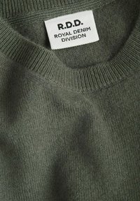 Dunkelgrüner Strickpullover mit geripptem Ausschnitt. Das Etikett trägt die Aufschrift "R.D.D. ROYAL DENIM DIVISION." Sanfte Textur, Nahaufnahme legt Details des Stoffes frei.