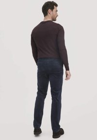 Dunkelburgunderfarbendes Langarmshirt kombiniert mit navyblauen Cordhosen. Glatter Stoff mit angepasst geschnittenem Design. Minimalistische Silhouette und einfarbige Farben.