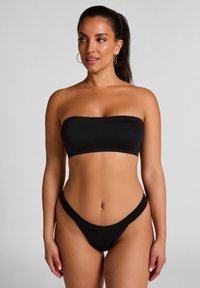 Zwart bikini set met een strapless top en hoge uitsnijdingen aan de onderkant, gemaakt van een gladde stof met minimale naden en een eenvoudig ontwerp.