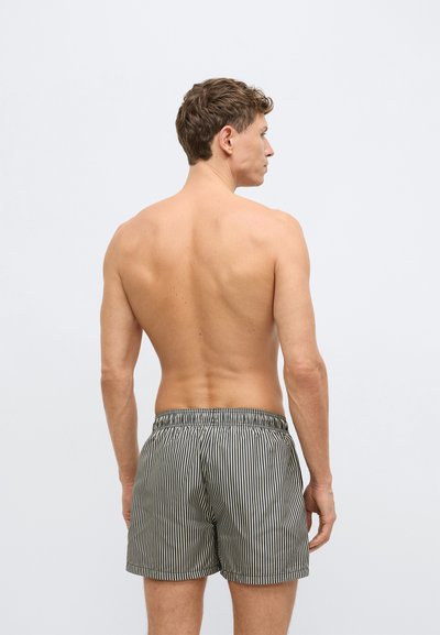 Ανδρικό ριγέ μαγιό βερμούδα με ελαστική μέση, με κάθετες μαύρες και άσπρες ρίγες και άνετη εφαρμογή, απεικονίζεται από πίσω.