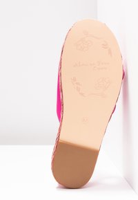 Semelle de sandale rose avec embossage floral, texte "alma en pena España", taille 37 et détail de bordure tissée visible.