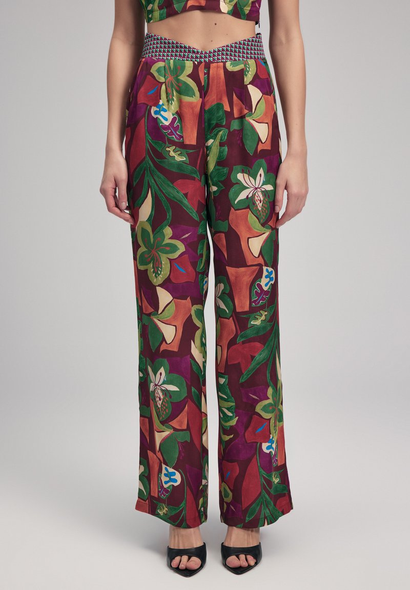 Brede bloemenbroek in levendige kleuren, met een meerkleurige elastische tailleband. De stof heeft een gladde textuur met een gedurfde bladdessin.