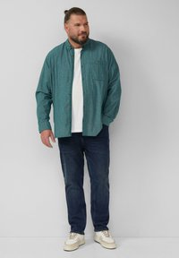Teal geruite blouse met knopen aan de voorkant, gecombineerd met een wit T-shirt, donkerblauwe jeans en lichte sneakers. Casual pasvorm en ontwerp.