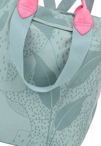 Bolso tote azul claro con un patrón floral, con asas texturizadas en rosa y azul. Incluye un bolsillo con cremallera para almacenamiento.