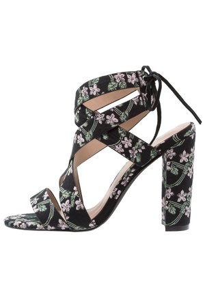 Schwarze Sandalette mit hohem Absatz, pink-grünem Blumenmuster, offenem Zehenbereich, gekreuzten Riemen und Knöchelbandverschluss.