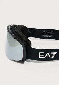 Černé lyžařské brýle s reflexními skly a nastavitelným elastickým popruhem s bílým logem EA7 na šedém pozadí.
