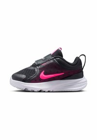 Zapatilla deportiva negra y rosa con parte superior de malla, tobillo acolchado, banda elástica y suela blanca. Presenta un prominente logo de Nike en rosa y detalles texturizados.
