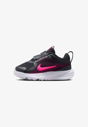 Zapatilla deportiva negra y rosa con parte superior de malla, tobillo acolchado, banda elástica y suela blanca. Presenta un prominente logo de Nike en rosa y detalles texturizados.