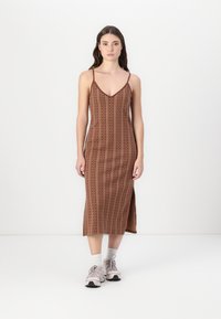 Ruskea kuvioitu midi-mekko kapeilla olkaimilla, V-pääntiellä ja sivuräjäytuksella, yhdistettynä vaaleisiin lenkkitossuihin. Sujuva texture ja istuva muotoilu.