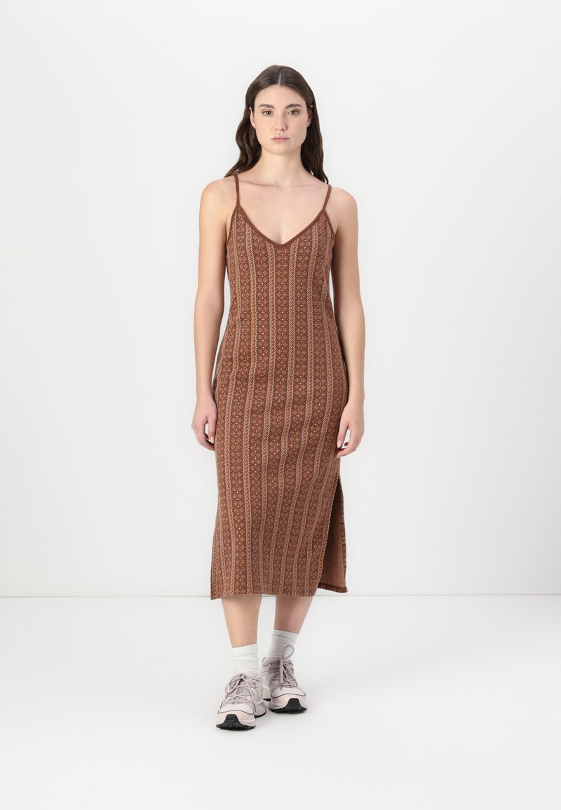 Ruskea kuvioitu midi-mekko kapeilla olkaimilla, V-pääntiellä ja sivuräjäytuksella, yhdistettynä vaaleisiin lenkkitossuihin. Sujuva texture ja istuva muotoilu.