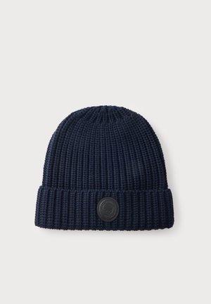 Bonnet en tricot côtelé bleu marine avec revers plié et petit patch logo rond noir sur le devant au centre.