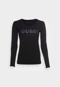Zwarte langgerekte t-shirt met lange mouwen, gemaakt van katoen, met een ronde halslijn, voorzien van "GUESS" en "EST.1981" in zilveren rhinestones over de borst.