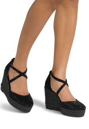 Black wedge shoes with a textured, woven heel, embellished with rhinestones on the toe and ankle strap. Crossover design accentuates the features.