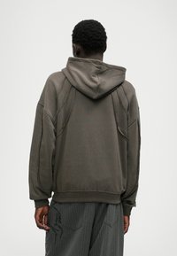 Hætte sweatshirt i afdæmpet olivengrøn, lavet af blødt stof, med en afslappet pasform, synlige syninger og et struktureret bagdesign.